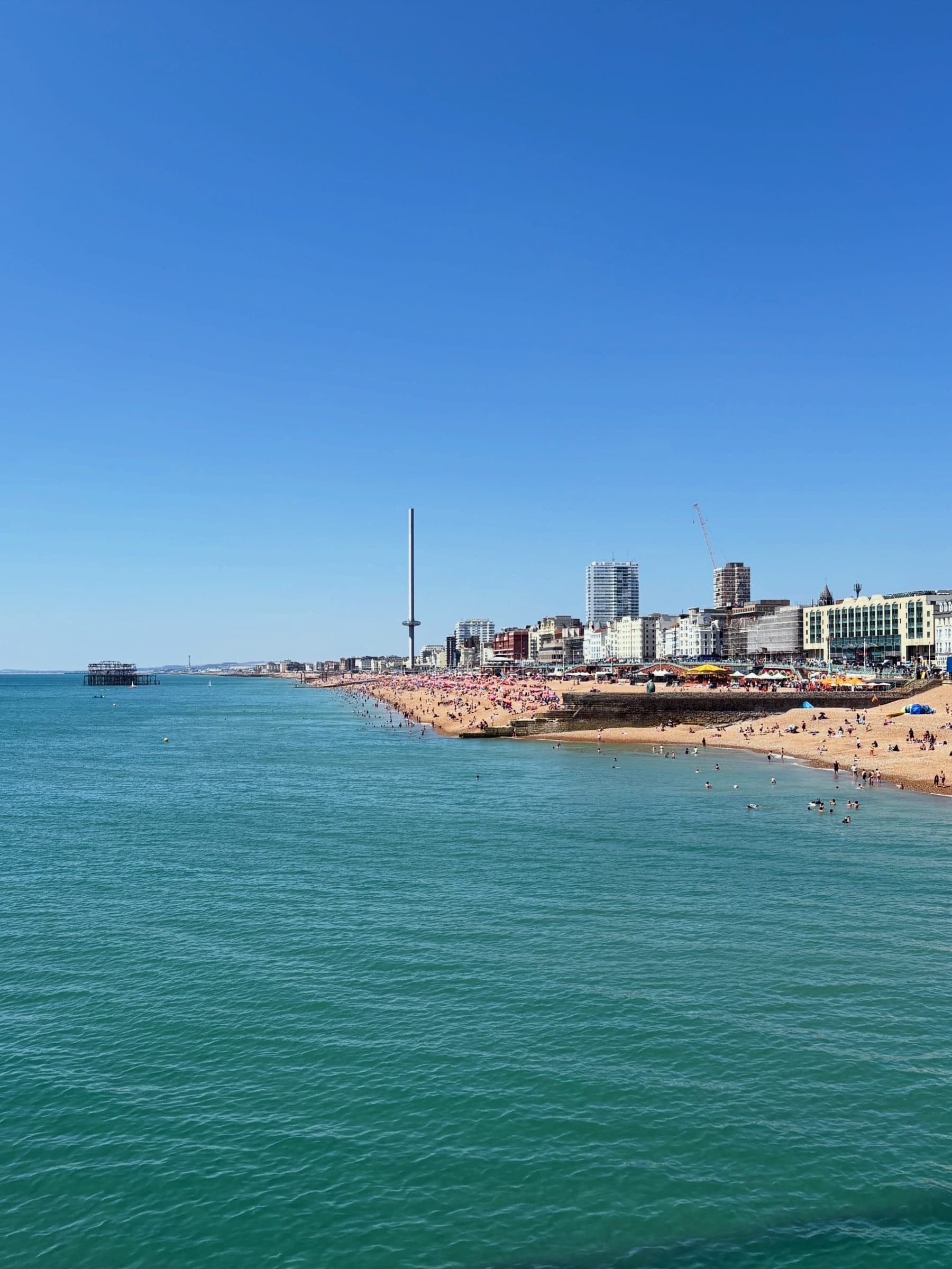 Empty beach and pier under a clear blue sky.