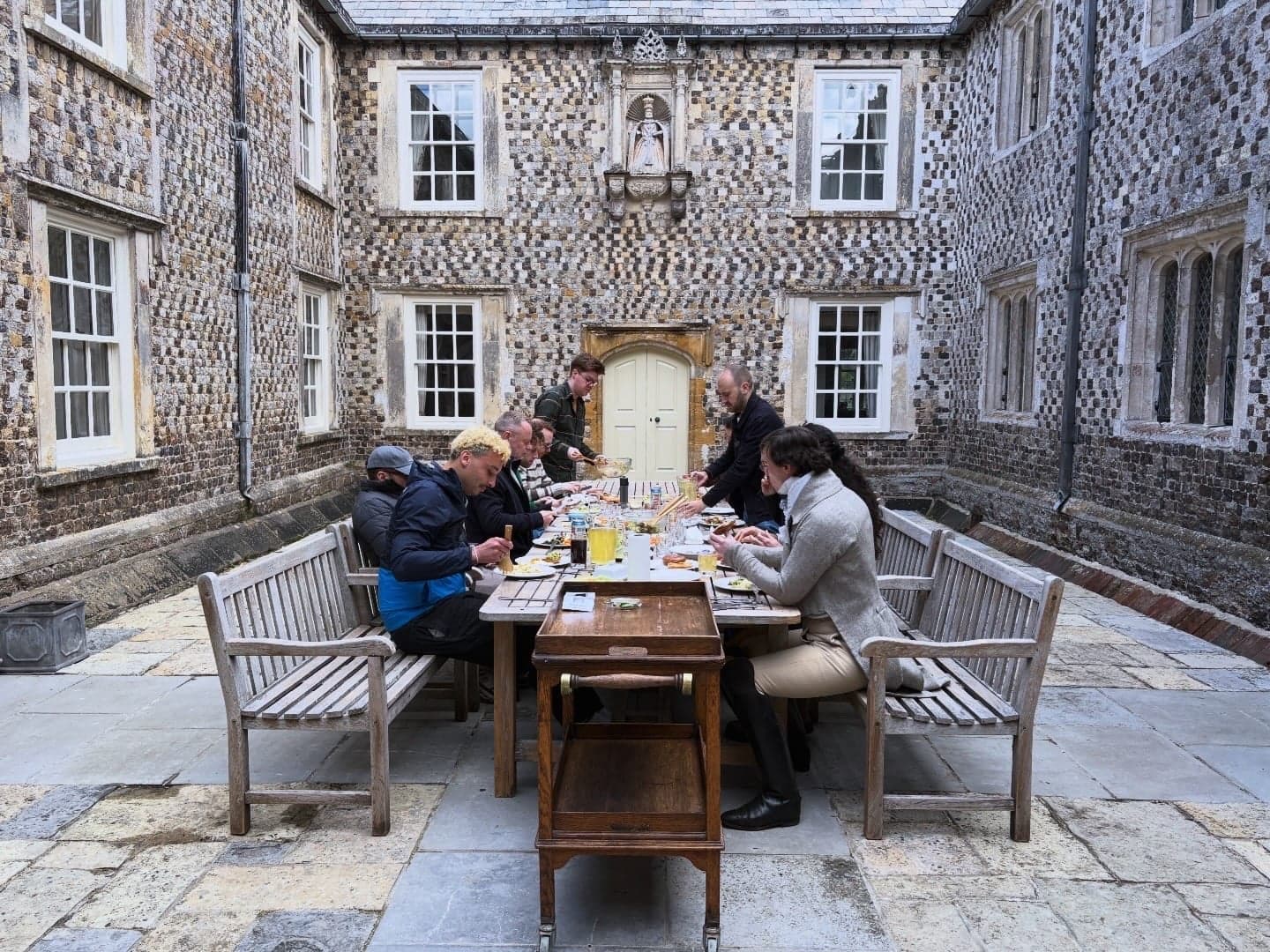 Guests share lunch at long tables in the manor's stone courtyard.