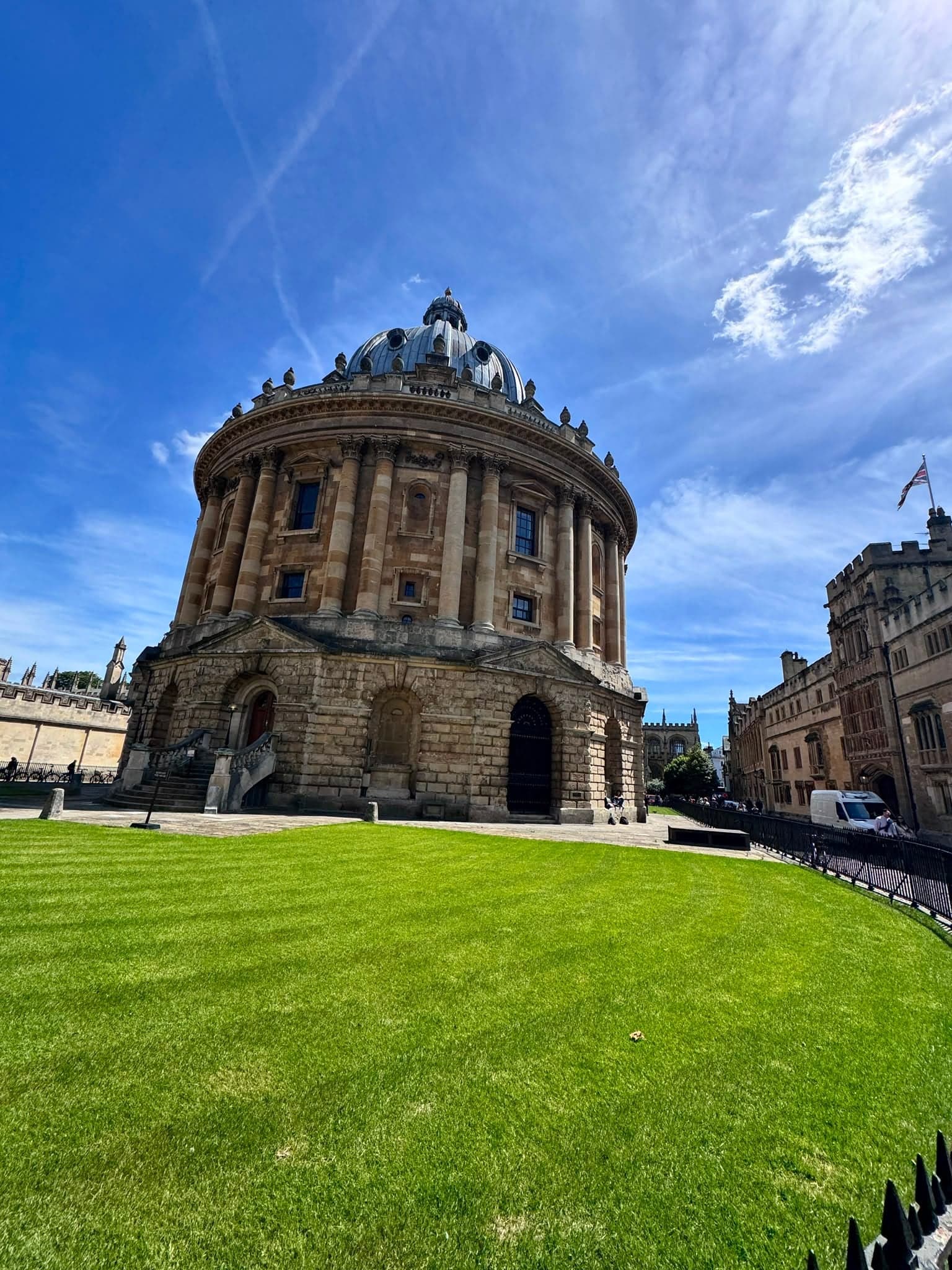 The Radcliffe Camera rises over its lawn under a blue sky.